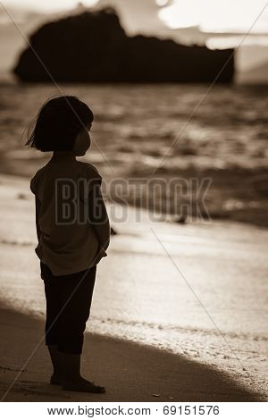 An Asian Little Girl Standing Alone On The Beach