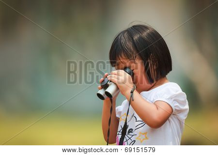 An Asian Little Girl Using A Binoculars By Her Own