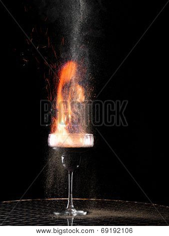 Flaming cocktail with gray pepper on dark background