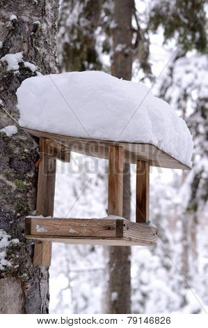 wooden bird table in winter and snow