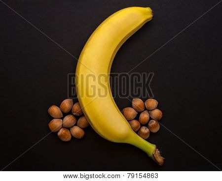 A banana and nuts on black background