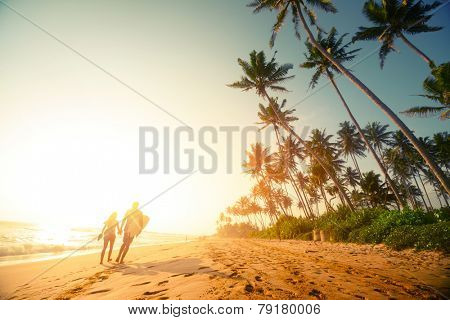 Couple walking on the sandy beach with palm trees