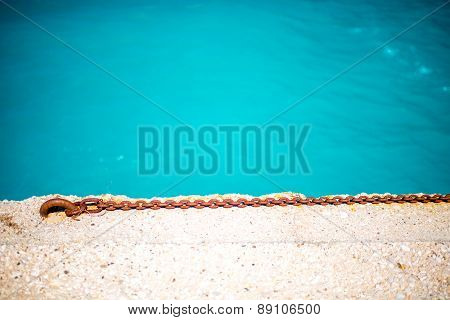Rusty chain on the concrete with water