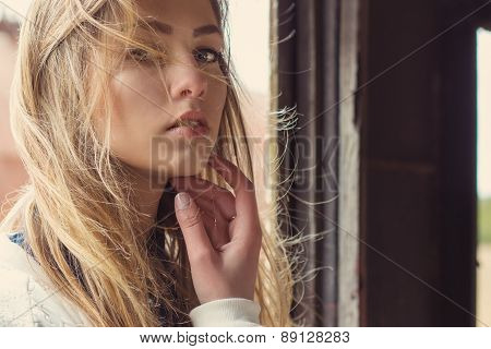 beautiful girl sitting in an abandoned train and a strong wind develops her hair