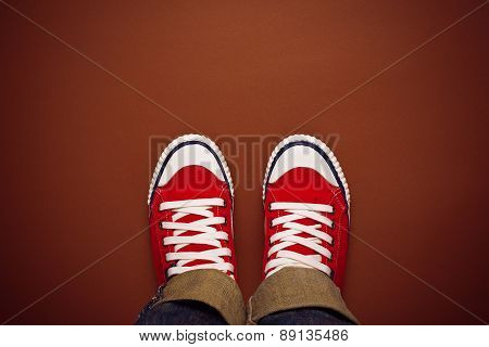 Feet From Above, Teenager In Sneakers Standing On Brown Background