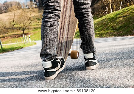 Legs and sneakers of a young boy and an edgewise longboard
