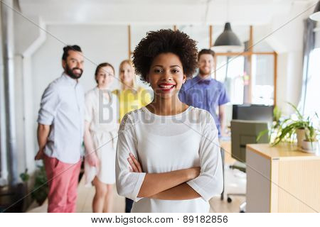 business, startup, people and teamwork concept - happy young woman over creative team in office