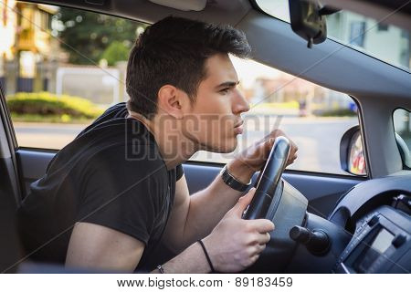 Young Man Leaning Forward on Steering Wheel of Car