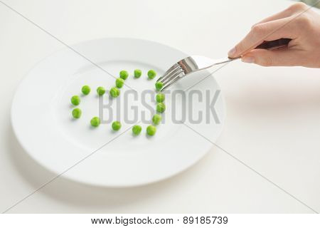 healthy eating, dieting, vegetarian food and people concept - close up of woman with fork eating peas in shape of heart