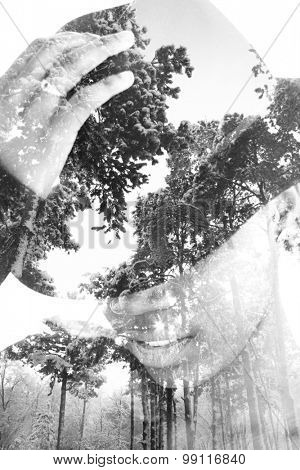 Multiple exposure portrait of woman wearing hat combined with photograph of trees covered with snow