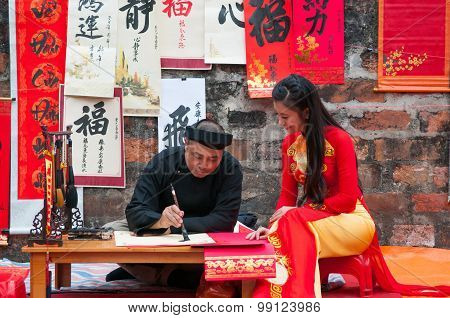 Old master write ancient letters for a girl in Aodai costume