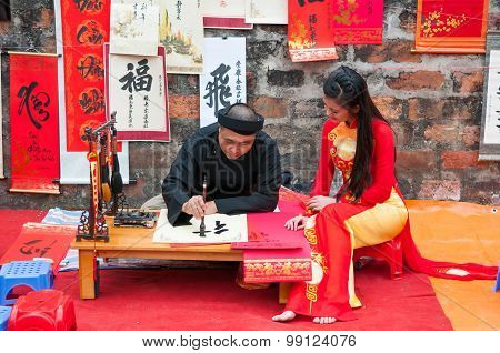 Old master write ancient letters for a girl in Aodai costume