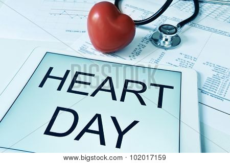 a red heart, a stethoscope and a tablet computer with the text heart day in its screen, with a filter effect