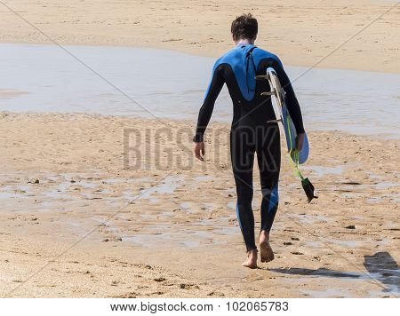 Surfer Walking Into The Warter On The Sun At The Beach