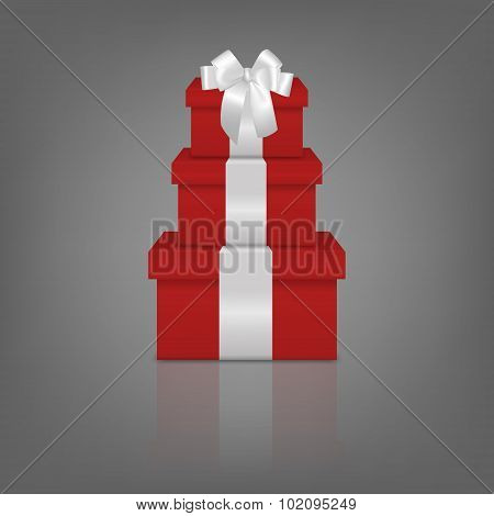 Stack of three realistic red gift boxes with white ribbon and bow