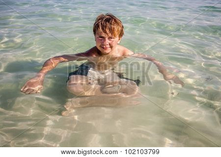 Cute Boy Enjoys Sitting In The Ocean