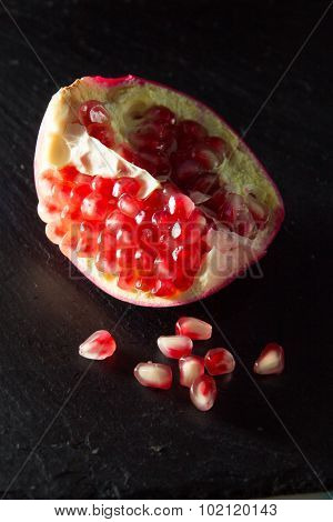 Small Heap Of Pomegranate Seeds On Black Slate Surface