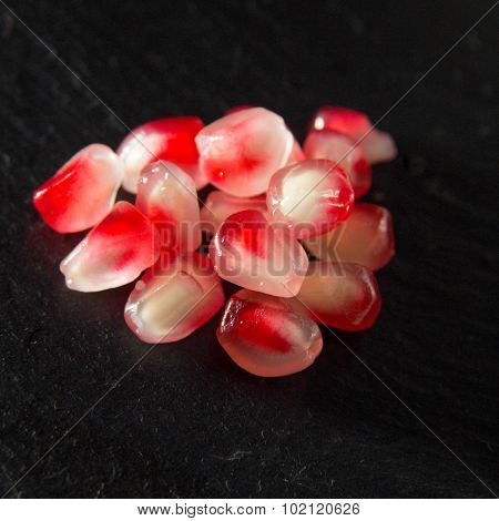 Small Heap Of Pomegranate Seeds On Black Slate Surface