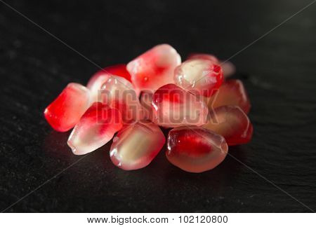 Small Heap Of Pomegranate Seeds On Black Slate Surface