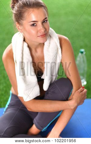 Beautiful young woman relaxing after exerscises on the grass 