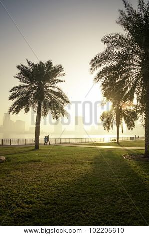 A couple walking in the morning at the creekside. A distant shot of people with their outdoor fitness regime.