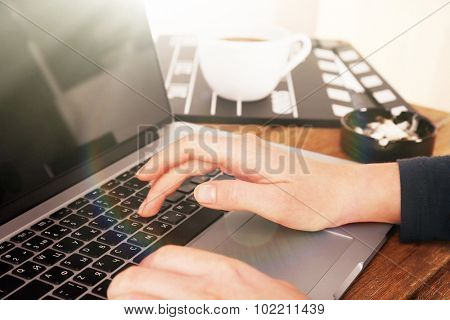 Female hands of scriptwriter working on laptop at desk on cupboard background