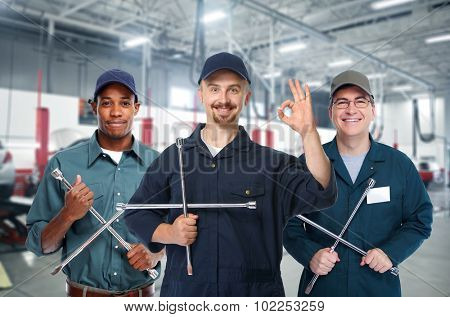 Smiling repairman with tire wrench in car repair service.