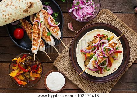 Chicken kebab with grilled vegetables and tortilla wrap.