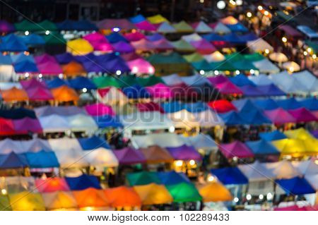 Abstract bokeh light at night of multiple colors flea market roof top view