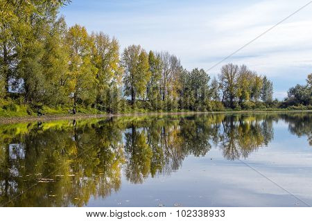 Autumn landscape on the river with fishermen