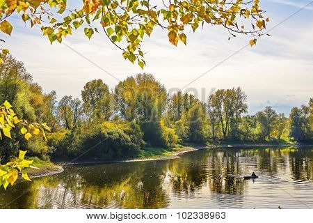 Autumn landscape with fisherman in a boat on the river