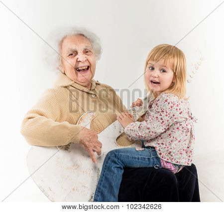 little girl on geatgrandmother knees having fun with quitar