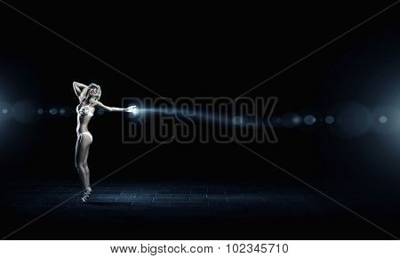 Hot young dancing woman in white bikini on dark background