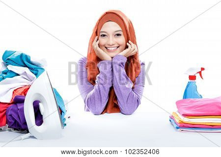Young Smiling Woman Wearing Hijab Sitting Between Fresh Clean Laundry