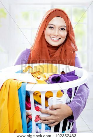 Housewife Wearing Hijab Carrying Laundry Basket Full Of Dirty Clothes