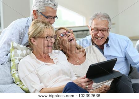 Group of senior friends with eyeglasses using digital tablet