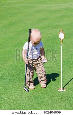 Cute Little Baby Boy Playing Golf On A Field