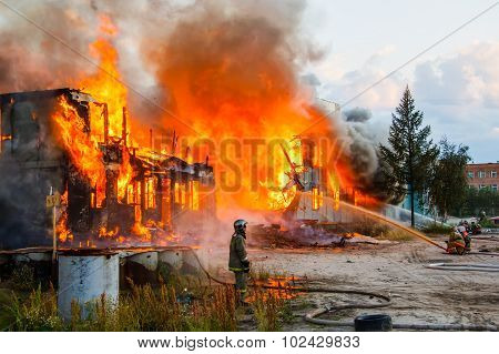 Novyy Urengoy, Russia - August 3,2015: Fireman extinguishes a burning old wooden residential house