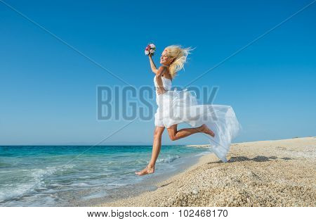 Young bride in wedding drees having fun on the beach in Greece