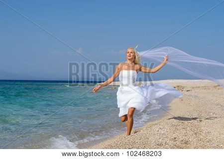 Young bride in wedding drees having fun on the beach in Greece
