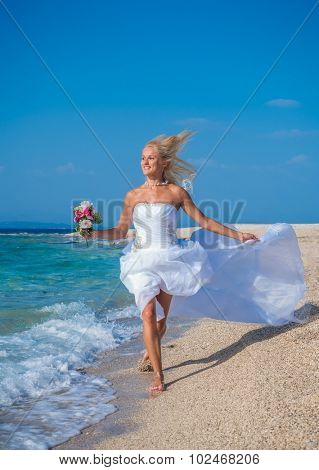 Young bride in wedding drees having fun on the beach in Greece