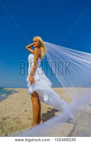 Young bride in wedding drees having fun on the beach in Greece