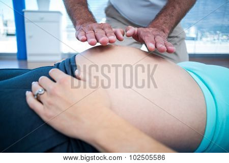 Therapist performing reiki on pregnant woman belly