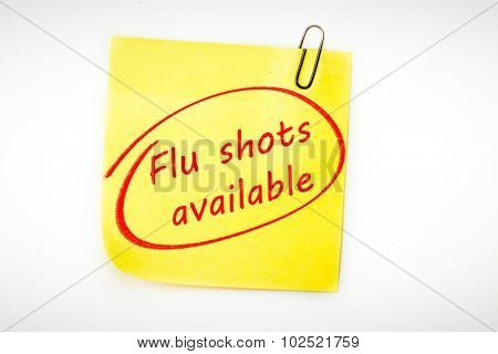 flu shots available against sticky note with grey paperclip