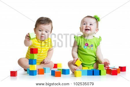 Two adorable kids playing with toys. Toddlers girl and boy sitting on floor. Isolated on white backg