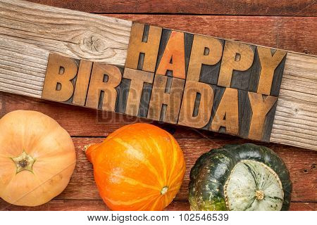 Happy Birthday greeting card - text in letterpress wood type printing blocks over rustic grained barn wood with winter squash