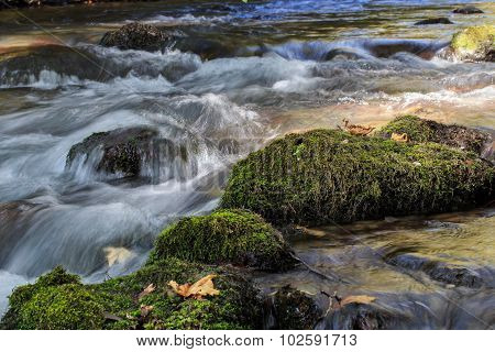 Flowing Water Over Stones With Green Moss.