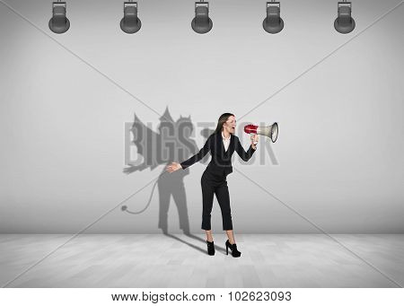 Businesswoman stands with shadow on the wall