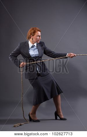 Businesswoman hauling at a rope