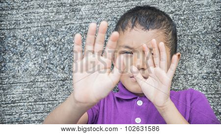 Young Asian boy using his hand to protect himself from physical abuse